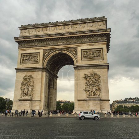 Téléchargez les photos : Le monument de l'Arc de Triomphe à Paris France avec un sombre paysage nuageux en arrière-plan - en image libre de droit