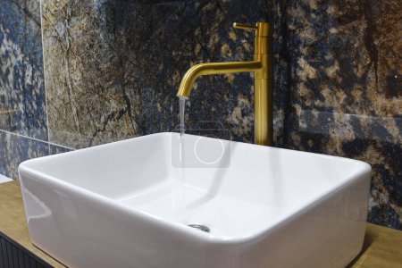 Foto de Un primer plano de un lavabo con grifo de oro en el baño moderno - Imagen libre de derechos