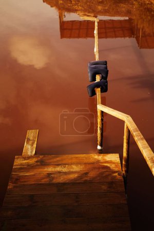 Foto de Un disparo vertical de un viejo muelle de madera en un agua salada roja - Imagen libre de derechos