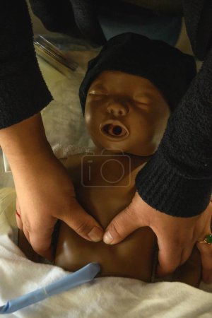Téléchargez les photos : Gros plan d'une femme faisant un massage cardiaque pour un bébé en réanimation plastique - en image libre de droit