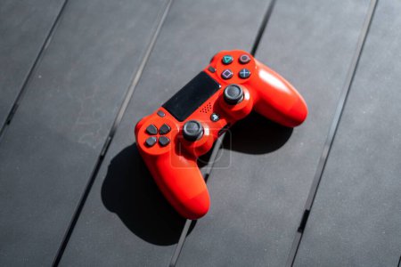 Téléchargez les photos : Une vue de dessus d'une manette PlayStation 4 ps4 rouge sur une table en bois gris - en image libre de droit