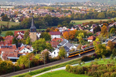 Photo for A drone shot of a train passing by beautiful city with autumn trees - Royalty Free Image