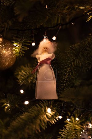 Foto de Un plano vertical de una dama ornamental colgada en un árbol de Navidad con luces - Imagen libre de derechos
