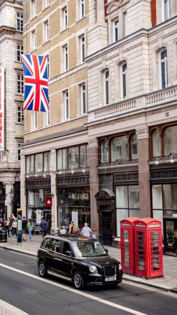 Téléchargez les photos : Le centre de Londres avec un taxi noir et une cabine téléphonique rouge, l'Union Jack accroché au-dessus - en image libre de droit