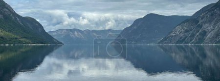 Photo for A landscape view of the rocky mountains reflected in water in Ardalsfjorden, Sognefjord area, Norway - Royalty Free Image