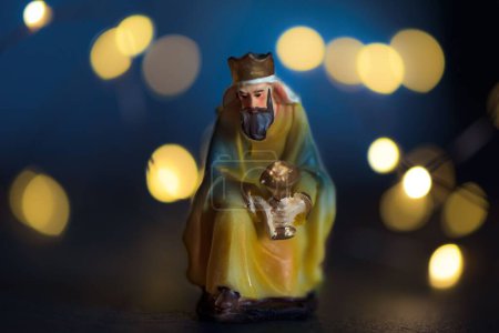Téléchargez les photos : Une petite figurine en porcelaine de Noël d'un roi sur fond de lumières de Noël - en image libre de droit