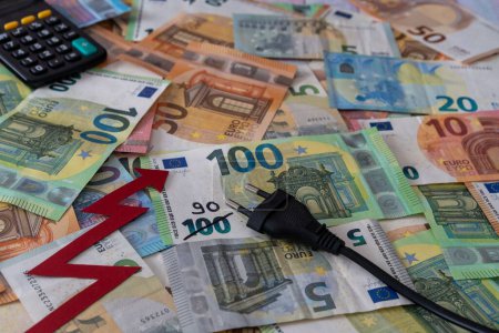 Foto de Una flecha roja creciente, calculadora y enchufe en el dinero de los billetes en euros, la crisis creciente del precio de la electricidad - Imagen libre de derechos