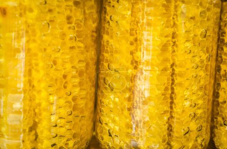 Téléchargez les photos : Le miel et le nid d'abeille dans des bouteilles en verre emballées pour la vente - en image libre de droit