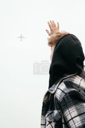 Foto de Un disparo vertical de un joven macho agitando su mano al avión volando en el aire - Imagen libre de derechos