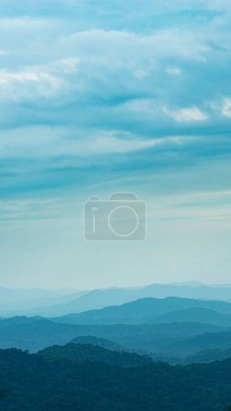 Photo for A vertical aerial shot of layered mountain range covered with greenery under a cloudy sky - Royalty Free Image
