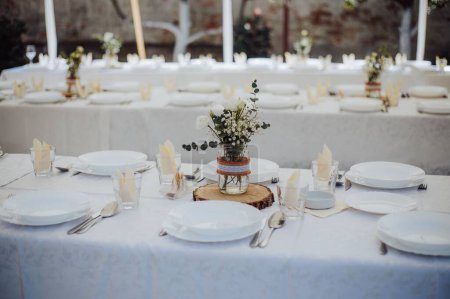 Photo for A closeup shot of the set table for a wedding ceremony, and flower decoration on tables, the concept of celebration of love - Royalty Free Image