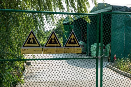 Photo for A closeup of three signs of Hazardous Waste Area on a factory gate in CHINA - Royalty Free Image