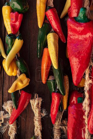 Photo for A vertical closeup shot of colorful chili ristras hanging on a wooden surface - Royalty Free Image