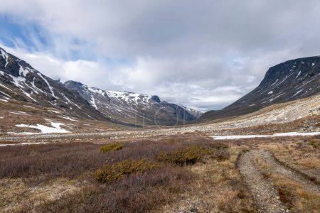 Téléchargez les photos : Une belle vue de la vallée sèche de Visladen près des montagnes enneigées à Piterstulen, Jotunheimen, Norvège - en image libre de droit