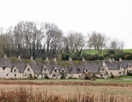 Photo for A row of historic quintessential Cotswold cottages with leafless trees in the background in Bibury, Gloucestershire, England - Royalty Free Image