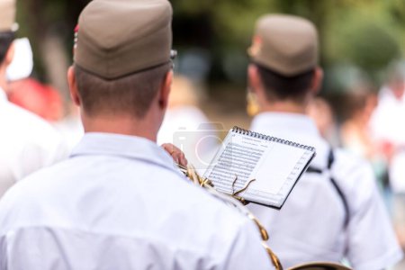 Téléchargez les photos : Brass band musiciens tenant des partitions par derrière dans un parc ensoleillé - en image libre de droit