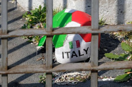 Téléchargez les photos : Une boule avec drapeau italien sur le sol derrière une grille métallique - en image libre de droit