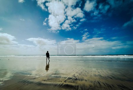 Téléchargez les photos : Une silhouette d'une personne sur une plage sous un ciel nuageux - en image libre de droit