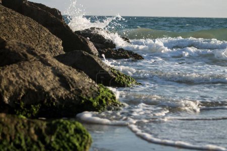 Foto de Las olas del mar chocando contra las grandes rocas en la orilla en un día soleado - Imagen libre de derechos
