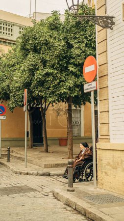 Foto de Un disparo vertical de una anciana en silla de ruedas en un streen en Sevilla, España - Imagen libre de derechos