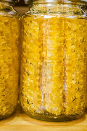 Foto de Un plano vertical de la miel y panal en botellas de vidrio empaquetadas para la venta - Imagen libre de derechos