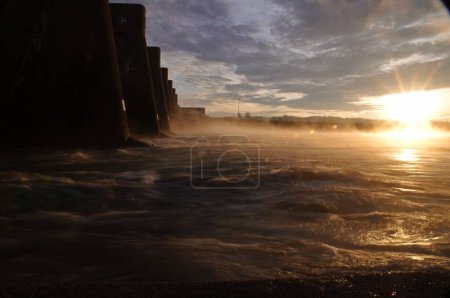 Téléchargez les photos : Une longue exposition du coucher du soleil scène de mer brillante avec côte falaise sous un ciel nuageux - en image libre de droit