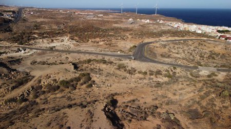 Photo for An aerial view of the highway leading through the desert in Tenerife, the Canary Islands in Spain, with a seascape in the background - Royalty Free Image
