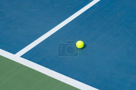 Téléchargez les photos : Un paysage d'un court de tennis bleu et vert avec une balle dessus par une journée ensoleillée - en image libre de droit