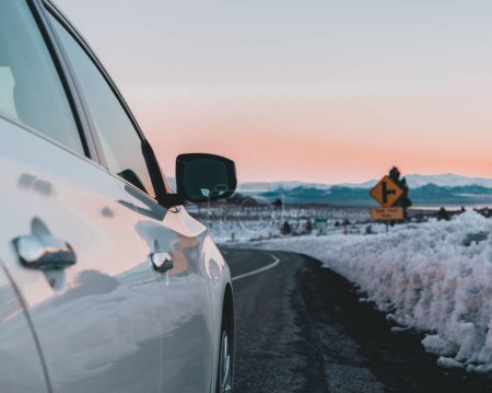 Téléchargez les photos : Une mise au point sélective du rétroviseur avant d'une voiture blanche garé sur une route dans une zone enneigée - en image libre de droit