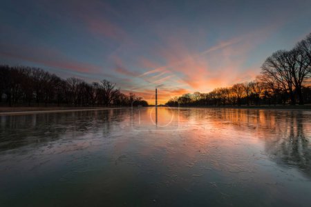 Téléchargez les photos : Le monument de Washington reflété dans les eaux gelées du lac au coucher du soleil - en image libre de droit