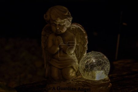 Téléchargez les photos : Un gros plan d'un petit ange sur un fond sombre - en image libre de droit
