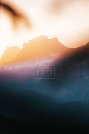 Téléchargez les photos : Une verticale d'un horizon flou de montagnes avec des forêts denses sous la lueur du coucher du soleil - en image libre de droit