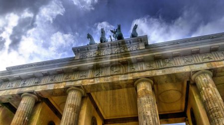 Foto de Un ángulo bajo de las estatuas del monumento neoclásico de la Puerta de Brandeburgo en la parte superior con rayos de luz del cielo - Imagen libre de derechos