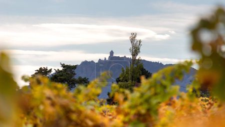 Téléchargez les photos : Une belle vue sur les arbres d'automne avec une église sur les montagnes en arrière-plan dans un ciel lumineux - en image libre de droit