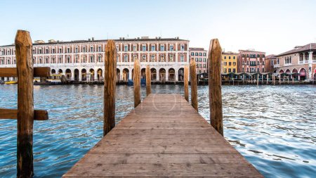 Foto de Un muelle frente a un hermoso lago rodeado de magníficos edificios en Venecia, Italia bajo un cielo despejado - Imagen libre de derechos