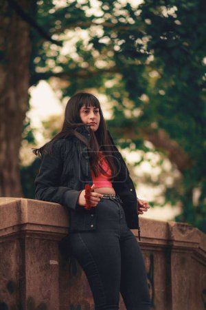 Photo for A vertical of a beautiful young woman with bangs posing for a photo while leaning on a stone building - Royalty Free Image
