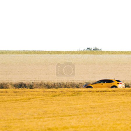 Téléchargez les photos : Une voiture jaune garée entre les champs jaunes récoltés - en image libre de droit