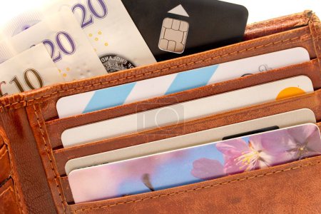 Foto de Un primer plano de una cartera de cuero marrón claro con tarjetas bancarias, billetes de diez y veinte libras - Imagen libre de derechos