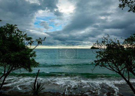 Foto de Una imagen escénica de las olas del mar salpicando una costa en un cielo nublado durante la puesta del sol - Imagen libre de derechos