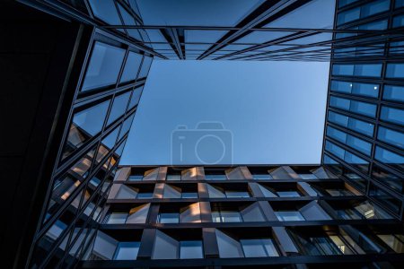 A horizontal low-angle shot of a modern glassy building in Zurich Switzerland with its mirror reflection