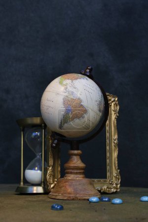 Foto de Un plano vertical de un globo y un reloj de arena sobre un fondo oscuro - Imagen libre de derechos