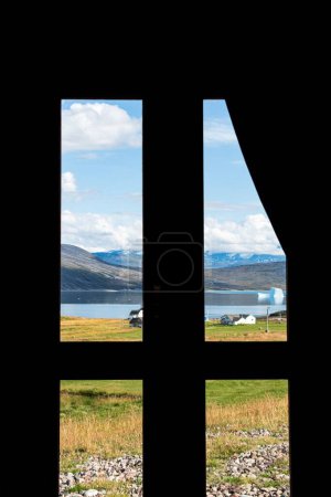 Photo for A vertical shot from the inside of a window overlooking a grass field on the coast of a lake - Royalty Free Image