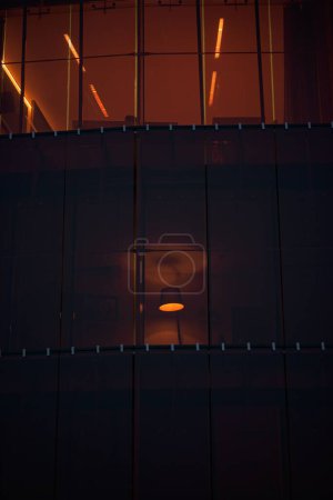 Téléchargez les photos : Plan vertical d'une lampe vue d'une fenêtre d'un grand bâtiment la nuit - en image libre de droit