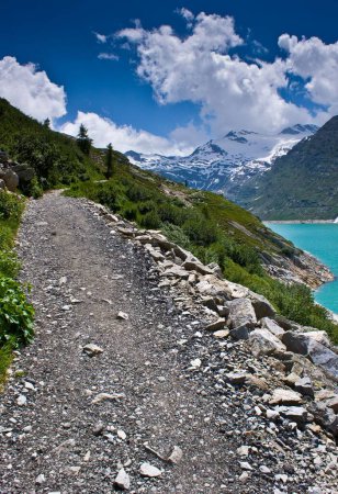 Téléchargez les photos : Un plan vertical d'un sentier rocheux avec le lac bleu et les montagnes enneigées en arrière-plan par une journée ensoleillée - en image libre de droit