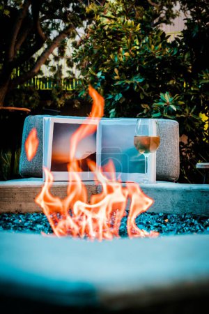 Téléchargez les photos : Un feu dans un feu de joie dans la cour de la maison avec du vin en arrière-plan - en image libre de droit