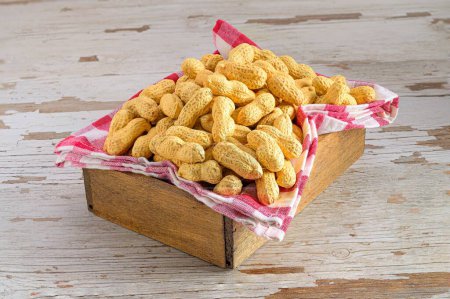 Photo for A closeup of some peanuts on a kitchen towel in a wooden box - Royalty Free Image