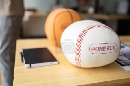 Photo for A closeup of a squishy baseball with a patch and a basketball out of focus on a wooden table - Royalty Free Image