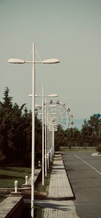 Téléchargez les photos : Un plan vertical de lampadaires avec une roue ferris en arrière-plan - en image libre de droit