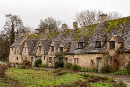 Photo for A road running alongside a row of historic quintessential Cotswold cottages in Bibury, England - Royalty Free Image