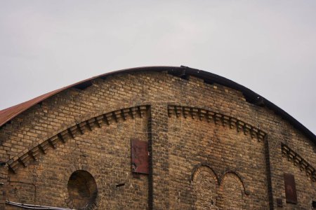 Téléchargez les photos : Un arc conçu haut de vieux bâtiment contre le ciel - en image libre de droit